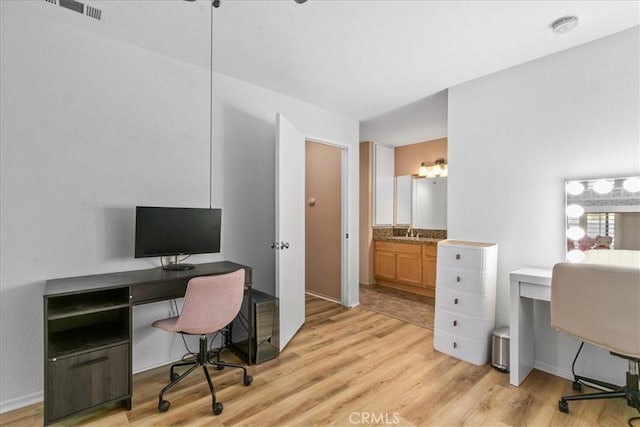 home office with light wood-style floors, a sink, and visible vents