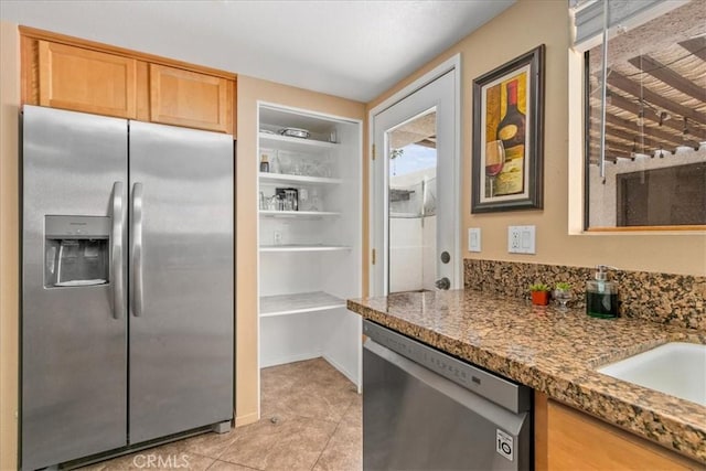 kitchen with light tile patterned floors, stainless steel appliances, and a sink