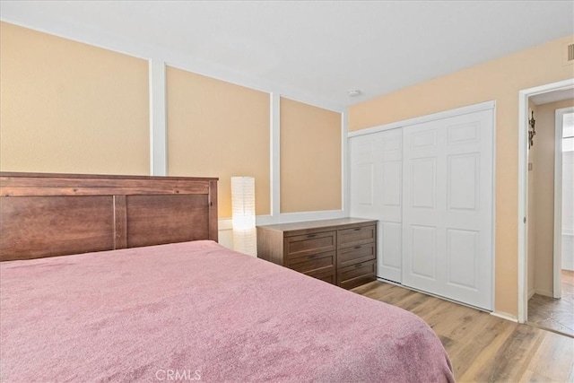 bedroom featuring baseboards, wood finished floors, and a closet
