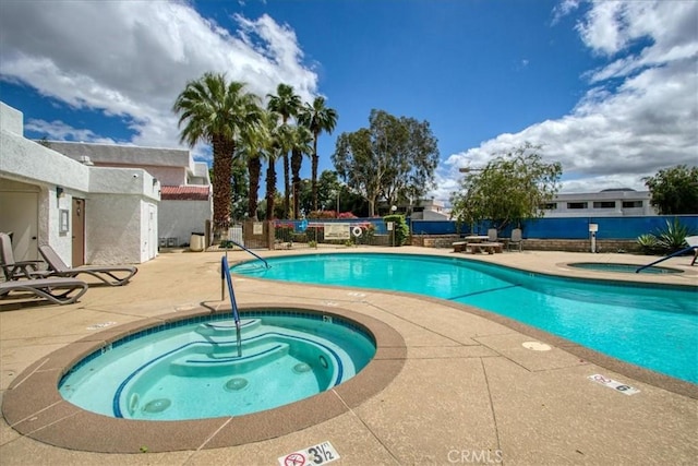 community pool with a patio, a community hot tub, and fence