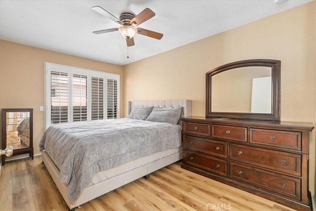 bedroom with baseboards, ceiling fan, and light wood-style flooring