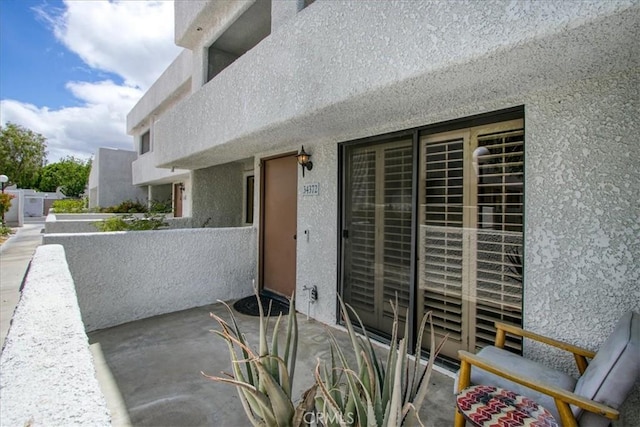property entrance with a balcony and stucco siding