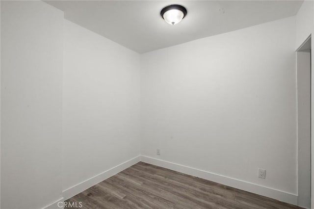 spare room featuring baseboards and dark wood-style floors