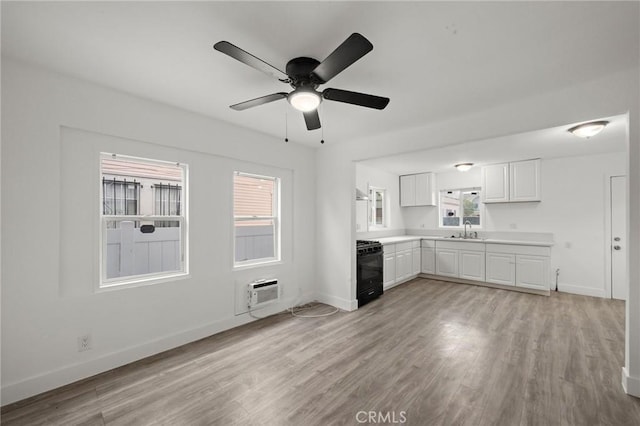 unfurnished living room with a sink, baseboards, light wood-style floors, and a ceiling fan