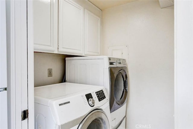 clothes washing area featuring cabinet space and washer and clothes dryer