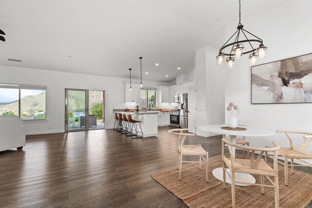 dining space featuring vaulted ceiling, dark wood finished floors, baseboards, an inviting chandelier, and recessed lighting