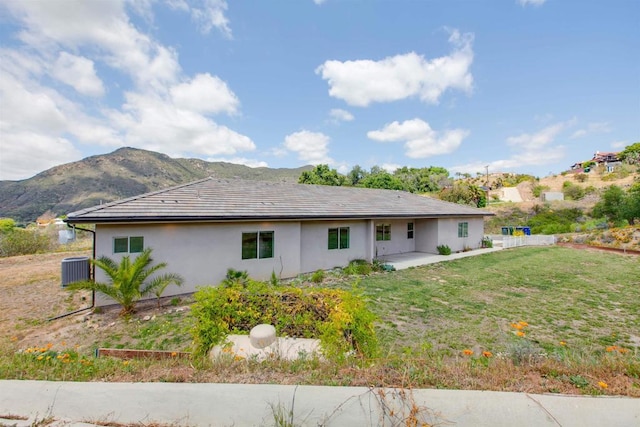 back of house featuring stucco siding, central air condition unit, a patio area, a mountain view, and a yard