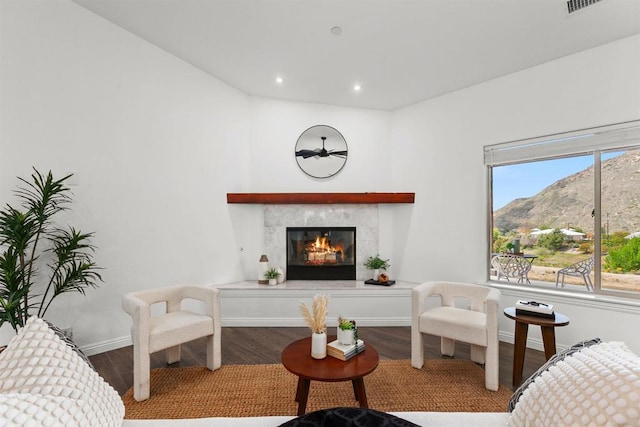 living area featuring a glass covered fireplace, wood finished floors, baseboards, recessed lighting, and a mountain view