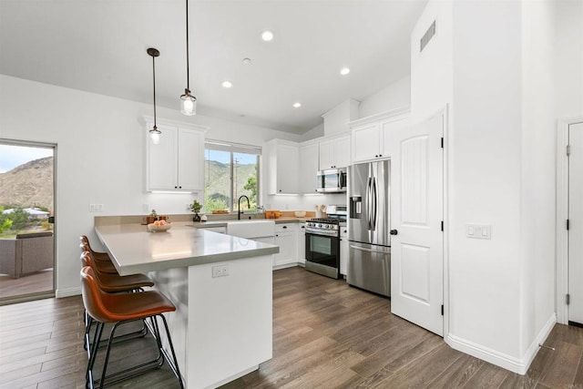 kitchen featuring appliances with stainless steel finishes, a kitchen breakfast bar, a peninsula, and white cabinets