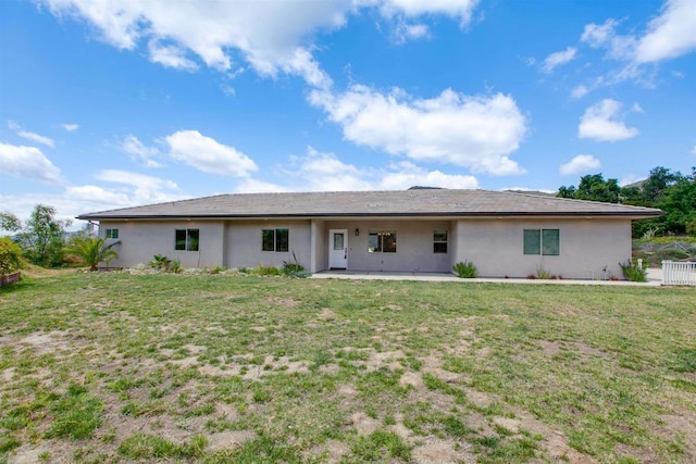 back of house featuring a lawn, a patio, and stucco siding