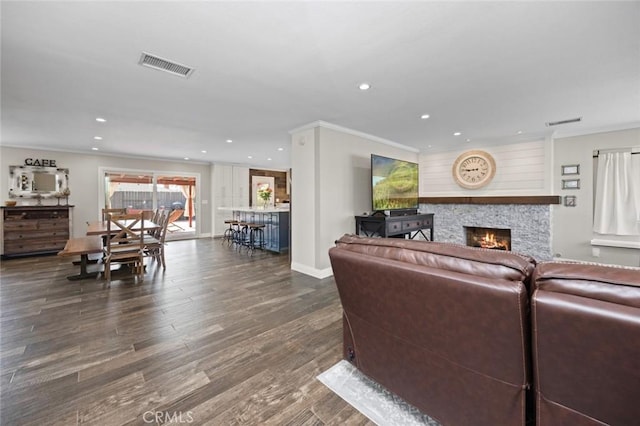living room featuring visible vents, recessed lighting, a warm lit fireplace, and ornamental molding