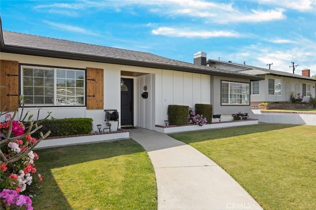 ranch-style house featuring board and batten siding, a chimney, and a front lawn