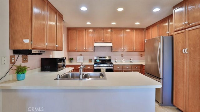 kitchen with a sink, light countertops, a peninsula, under cabinet range hood, and stainless steel appliances