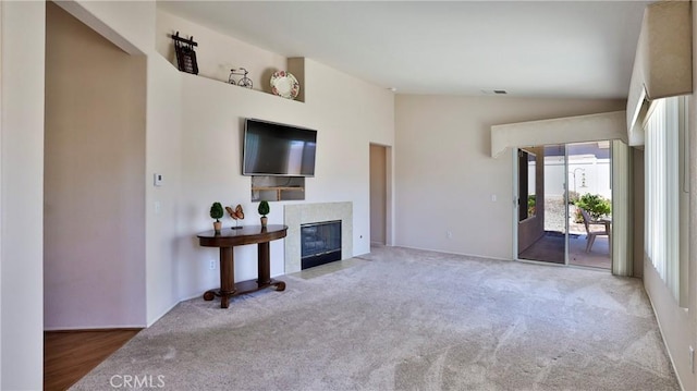 unfurnished living room featuring carpet flooring, vaulted ceiling, and a tile fireplace