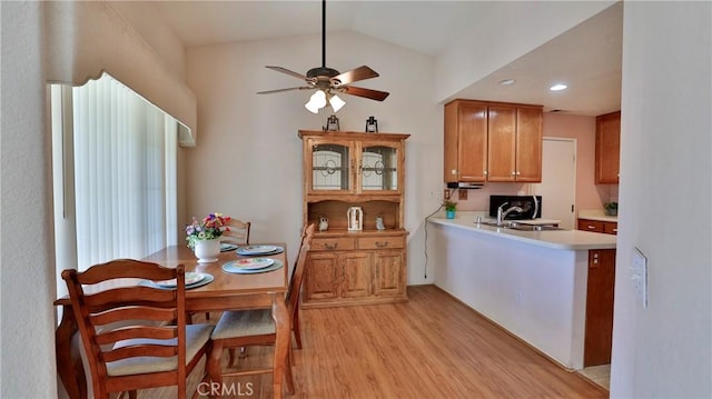 kitchen featuring brown cabinetry, light wood-style floors, ceiling fan, light countertops, and vaulted ceiling