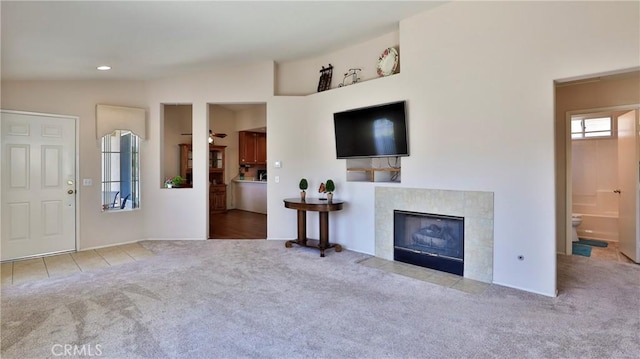 unfurnished living room with carpet flooring, recessed lighting, a tiled fireplace, and lofted ceiling