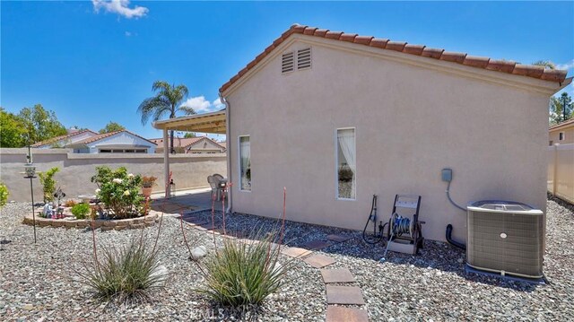 back of property featuring fence, central AC unit, stucco siding, and a patio area