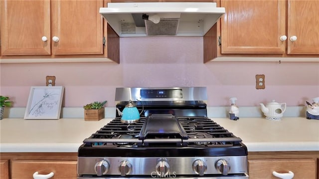 kitchen with wall chimney range hood, light countertops, and stainless steel range with gas cooktop