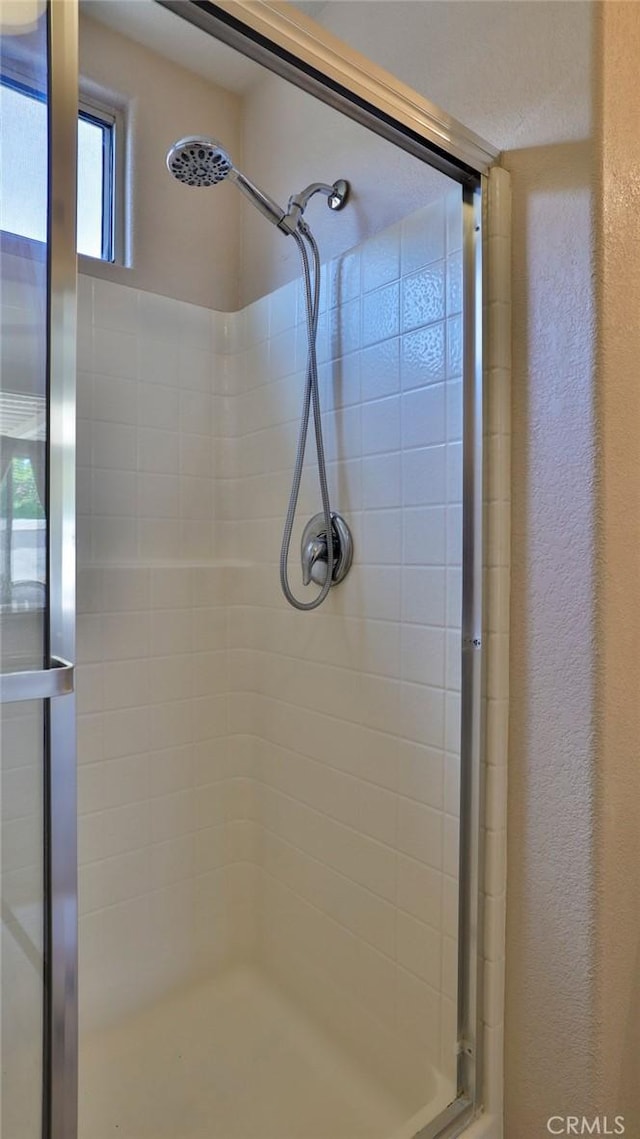 bathroom featuring a textured wall and a stall shower