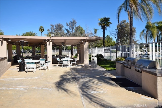 view of patio with fence, outdoor dining space, a grill, and exterior kitchen