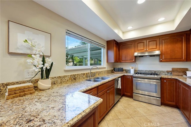kitchen featuring light tile patterned flooring, light stone countertops, under cabinet range hood, a sink, and appliances with stainless steel finishes