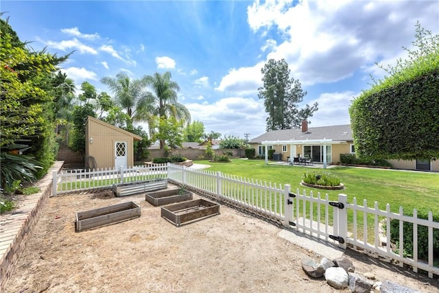 view of yard featuring a garden, an outbuilding, a patio area, a fenced backyard, and a storage unit