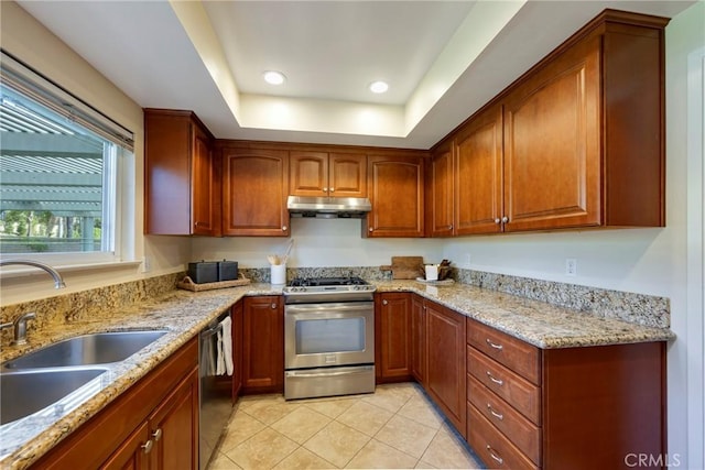 kitchen featuring light tile patterned flooring, stainless steel range with gas cooktop, under cabinet range hood, a sink, and dishwasher