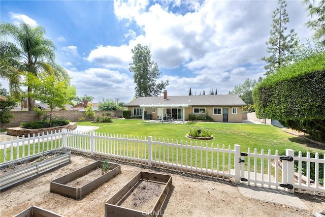 rear view of house with a lawn, a garden, fence private yard, and a patio area