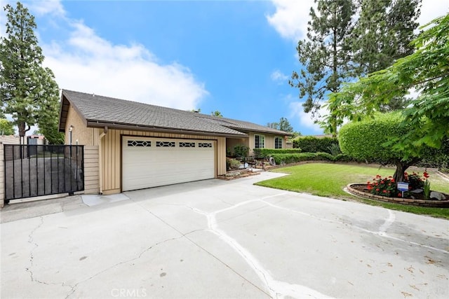 ranch-style home with an attached garage, driveway, a gate, and a front lawn