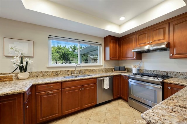 kitchen featuring light stone counters, a sink, under cabinet range hood, and stainless steel appliances