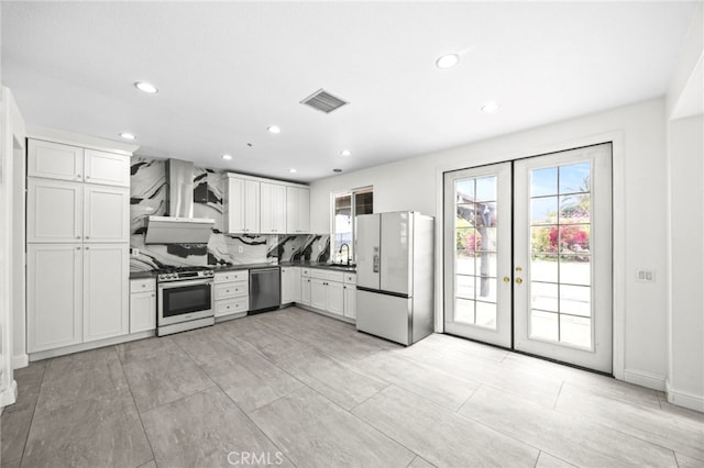 kitchen with visible vents, appliances with stainless steel finishes, tasteful backsplash, a sink, and wall chimney exhaust hood