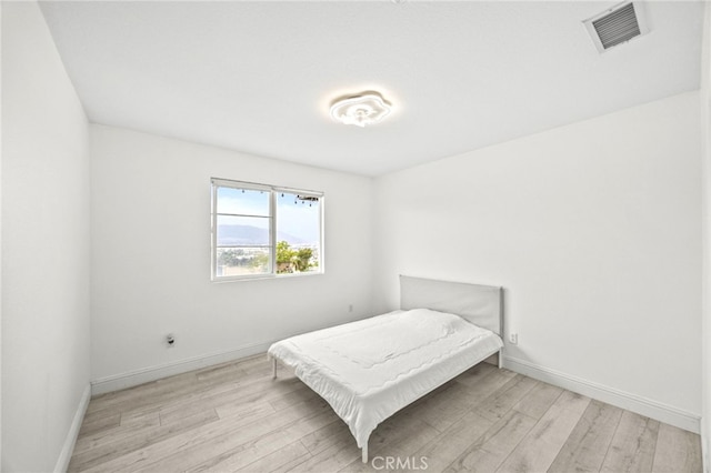 bedroom featuring baseboards, light wood finished floors, and visible vents