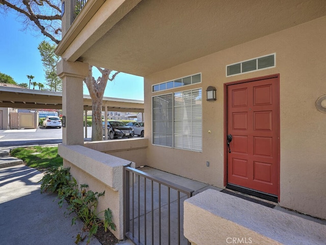 entrance to property with covered porch and stucco siding