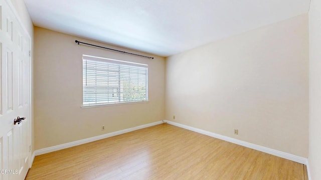 spare room featuring baseboards and light wood-type flooring