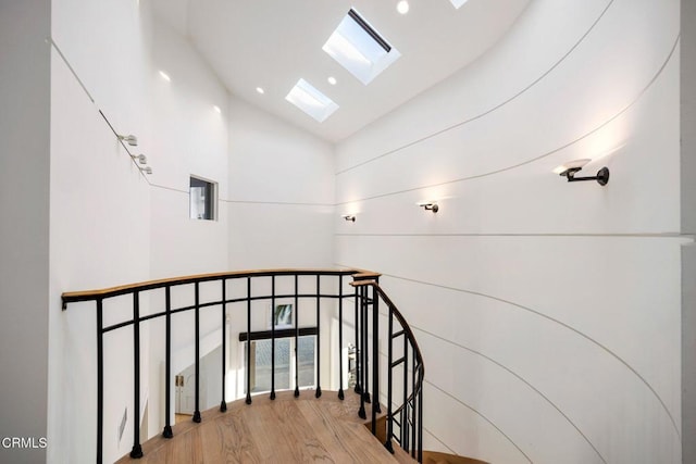 stairs featuring wood finished floors and lofted ceiling with skylight