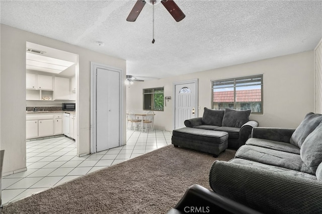 living room featuring light tile patterned floors, a ceiling fan, a textured ceiling, and visible vents