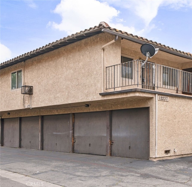 exterior space with an attached garage, stucco siding, and a balcony