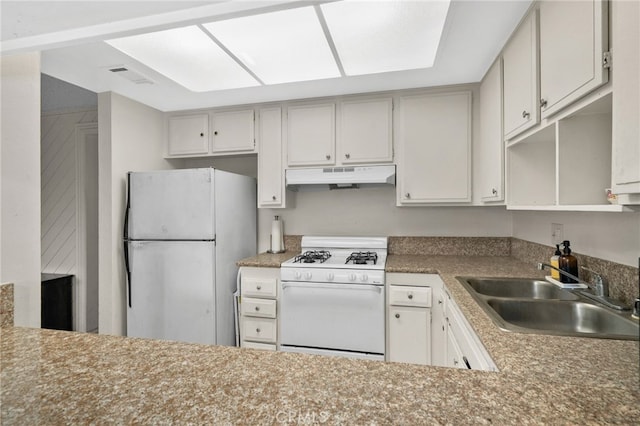 kitchen with a sink, under cabinet range hood, white appliances, and visible vents