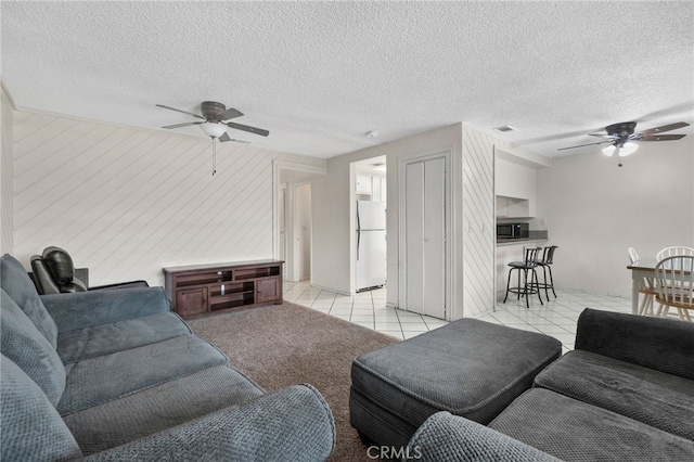 living area featuring visible vents, a textured ceiling, ceiling fan, and light tile patterned flooring