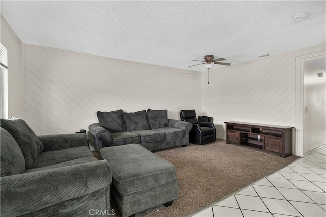 living area featuring a textured ceiling, ceiling fan, visible vents, and light colored carpet