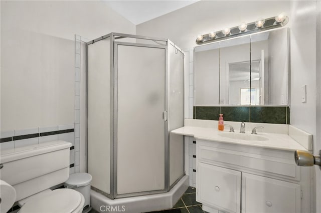 bathroom featuring toilet, tile walls, a shower stall, and vanity