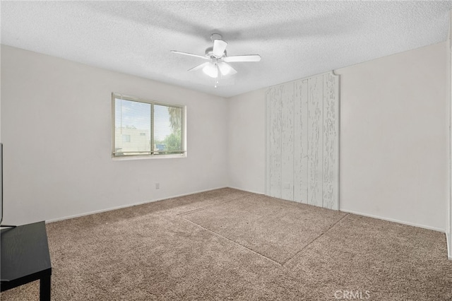 carpeted empty room with a ceiling fan and a textured ceiling