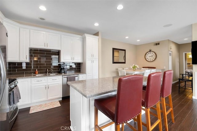 4 Mosaic, Aliso Viejo, CA 92656 - kitchen featuring visible vents, dark wood-style flooring, light stone counters, a sink, and stainless steel appliances