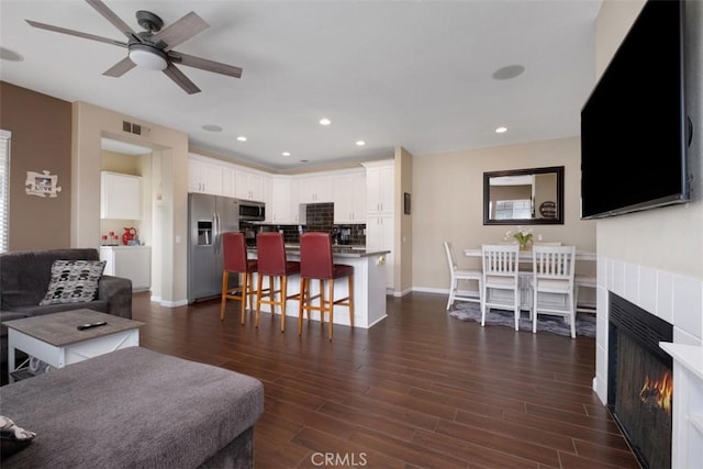 4 Mosaic, Aliso Viejo, CA 92656 - living room with a warm lit fireplace, ceiling fan, dark wood finished floors, baseboards, and visible vents