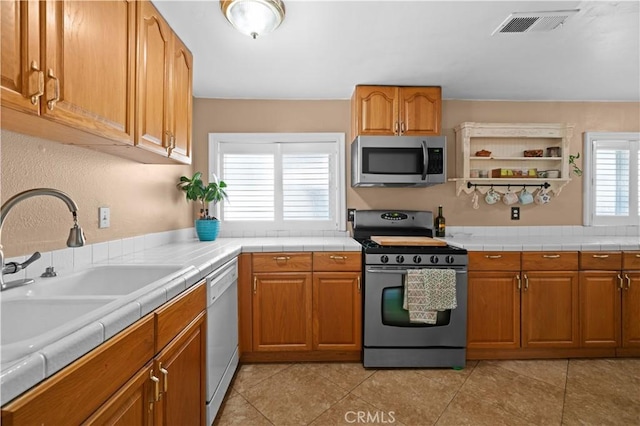kitchen with a sink, stainless steel appliances, brown cabinets, and visible vents