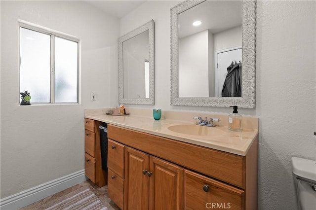 bathroom with toilet, baseboards, and vanity