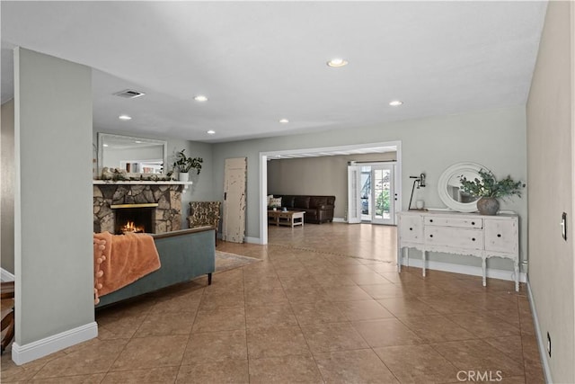 interior space with tile patterned floors, a stone fireplace, recessed lighting, baseboards, and visible vents
