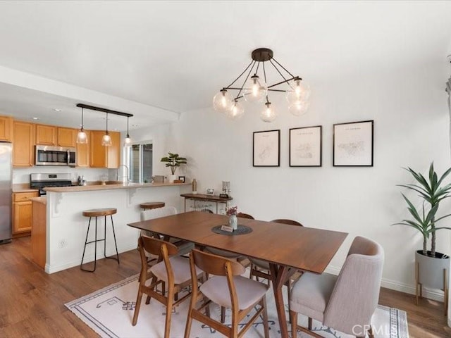 dining space with baseboards, an inviting chandelier, and wood finished floors