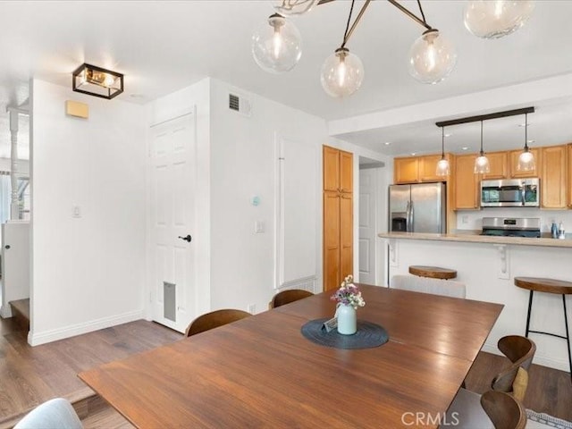 dining room with baseboards, wood finished floors, and visible vents
