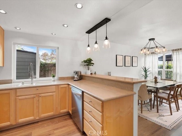kitchen with a sink, light brown cabinetry, stainless steel dishwasher, and a peninsula